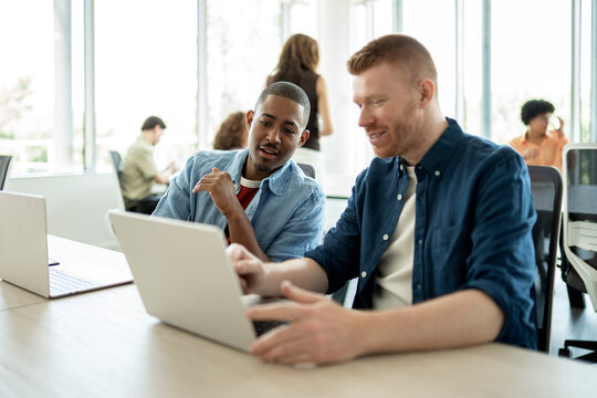Businessmen collaborating on laptop in modern office