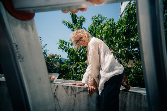 Person Working Outdoors With a Ladder on a Bright Sunny Day