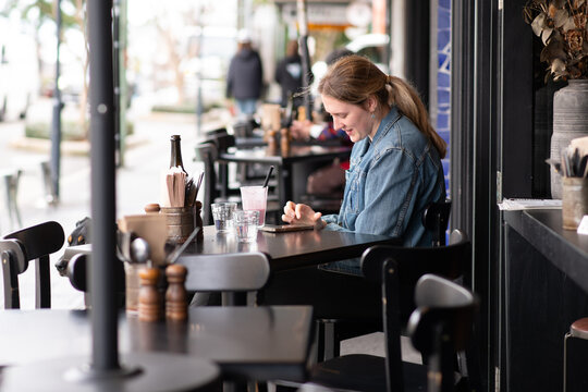 Woman Using Smartphone at Outdoor Cafe