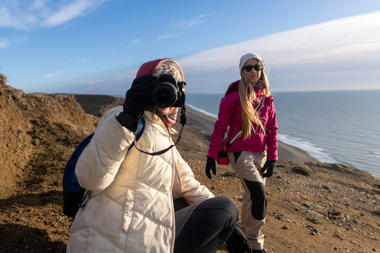 Two Women Enjoying Photography by the Coast During a Sunny Day