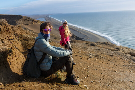 Couple Enjoying a Scenic View on a Coastal Cliff in Sunlight