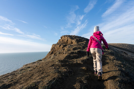 Hiker Ascending a Coastal Ridge on a Sunny Day