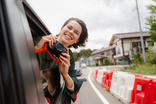 A woman takes pictures from a car