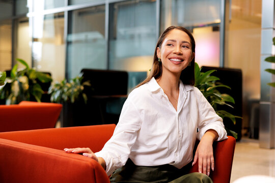 Business Casual Woman Relaxing on Red Chair in Office Lounge