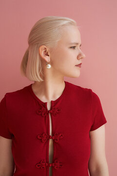 Woman in red top poses against a pink background
