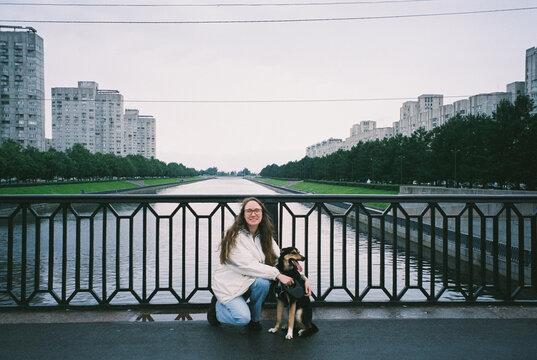 Woman Posing with Dog on Urban Bridge Over Canal
