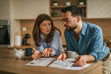 Couple having financial discussion in kitchen over bills © Miljan Živković