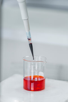 Pipette over beaker with red liquid