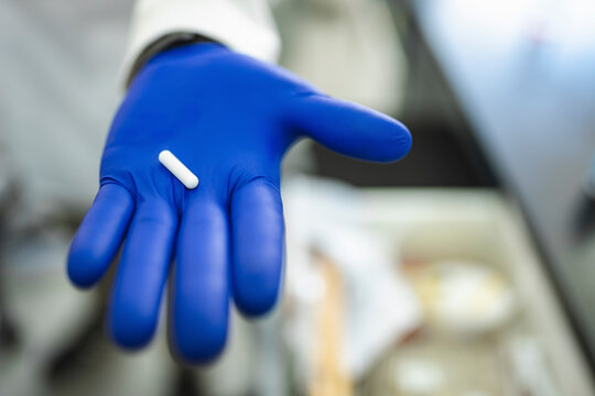 White capsule on blue glove