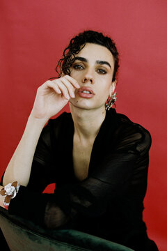 Queer model posing with hand on face and flower earrings