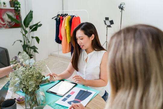 Asian designer showing dress design to client 