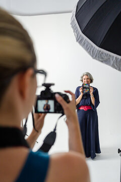 Photographer taking photo of woman holding color checker