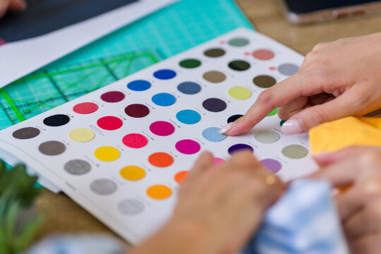 Fashion designers choosing fabric colors from catalog 