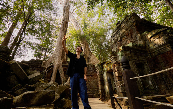 Man standing under tree ruins Siem Reap