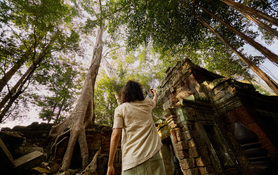 Person photographing at temple trees Siem Reap