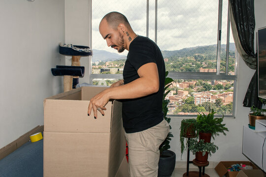 Man unpacking a large box in an apartment with city view