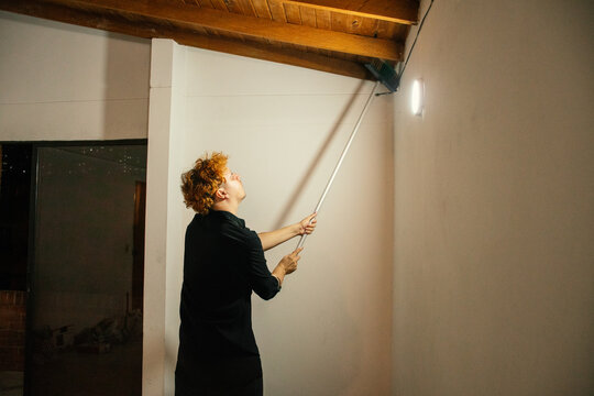 Person painting a wall with a broom in a cozy interior space