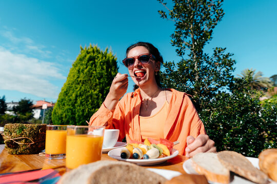 Young woman eating delicious fruit for breakfast outdoors