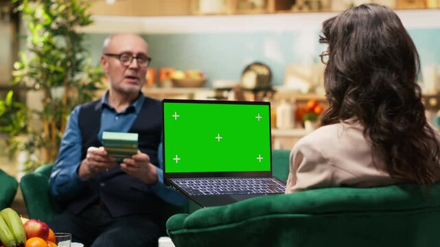 Chroma key screen on laptop with old woman and man relaxing in living room, taking pills and vitamins during daily living retirement lifestyle. Quality of life and longevity for pensioners.