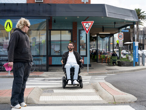Disabled man in wheelchair  Crossing Street with support worker