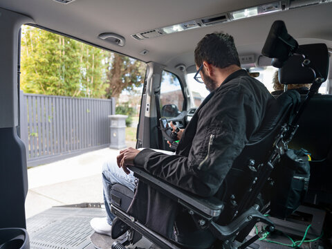 Man in a Wheelchair Using Smartphone in Accessible Vehicle