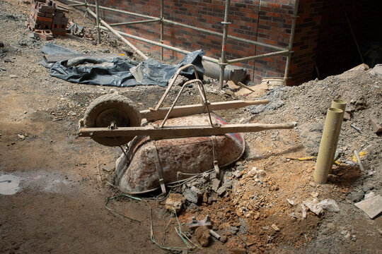 Construction site with wheelbarrow and building materials on ground