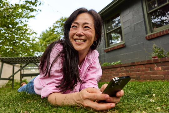 Asian woman laying down using her phone 