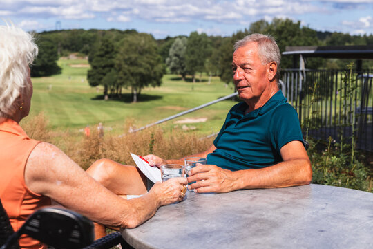 Senior Man Hydrating at an Outdoor Table