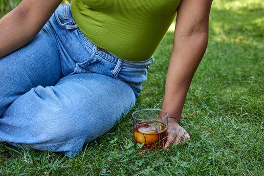 Young woman drinking a cocktail sitting on the grass