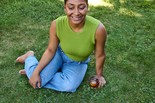 Young woman drinking a cocktail sitting on the grass