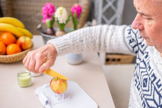 Senior man using adaptive non-slip cutting board for disabled with apple holder, inclusive kitchen aid people one hand mobility, rehabilitation process, stroke survivors, arthritis patients home care,