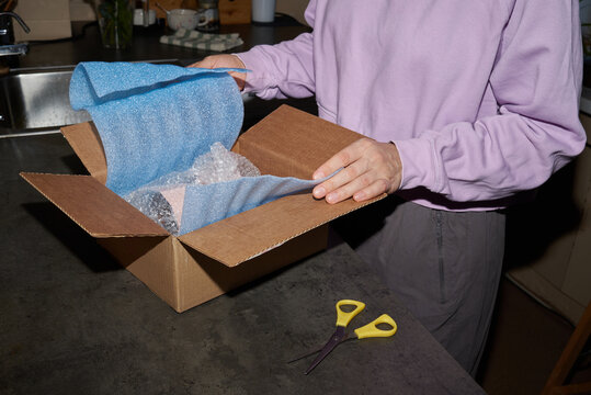 Unboxing a package wrapped in bubble wrap on a kitchen countertop.