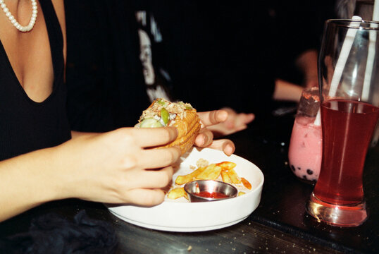 Person eating sandwich with fries and drinks

