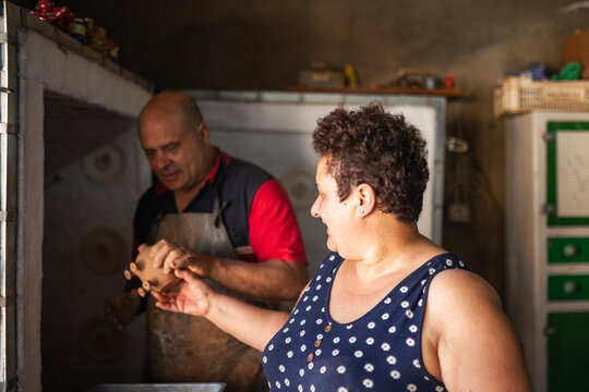 Married potters placing clay pieces into kiln