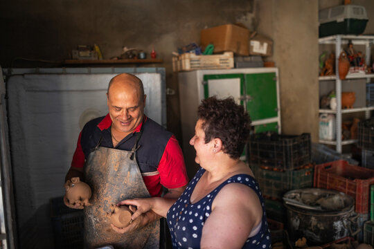Married potters placing clay pieces into kiln
