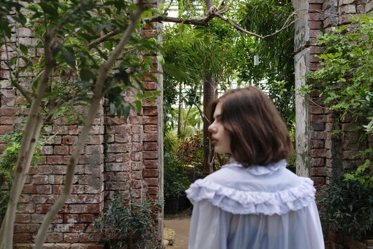 Young woman exploring lush garden paths surrounded by greenery 