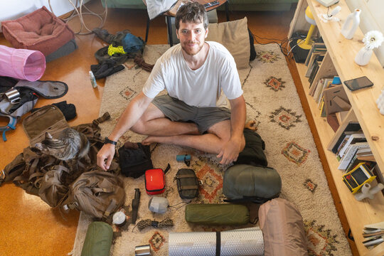 Man Preparing Hiking Gear with Cat