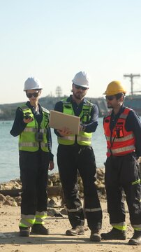 Civil engineering project managers executing coastal infrastructure development. Technical workforce discussing waterfront structural mechanics utilizing laptop database.
