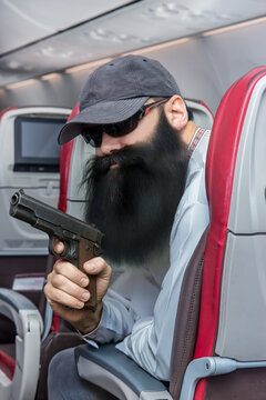 Bearded man looks like a terrorist sitting in a flying plane and holding a gun in his hand