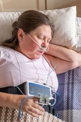 Woman resting in bed with home medical monitoring device, nasal cannula oxygen, apnea monitoring,...