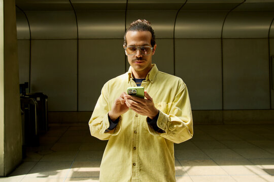 Man standing indoors using smartphone in London station