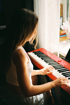 Woman playing a red and white keyboard in natural light