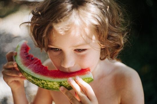 Little girl tasting ripe watermelon outside 