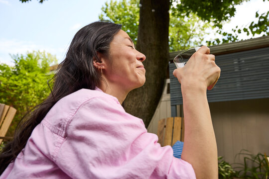Middle aged asian woman drinking a cocktail outside