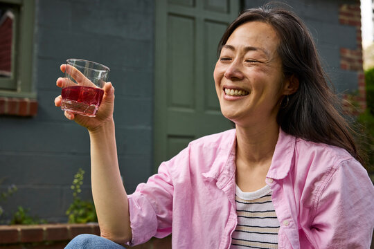 Middle aged asian woman drinking a cocktail outside