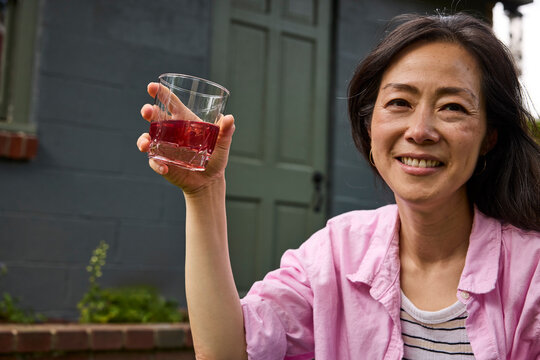 Middle aged asian woman drinking a cocktail outside