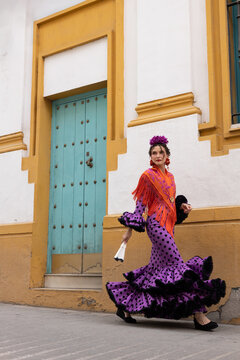 Woman in traditional polka dot flamenco dress walking by colorful wall