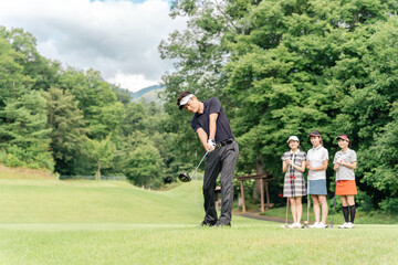 Obraz premium A male golfer hitting a tee shot at a golf course with his companion watching his swing