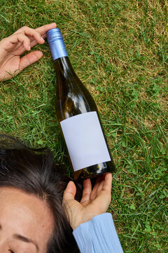 Woman laying on grass with a bottle of wine