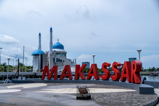 Makassar, Indonesia - February 15, 2026 : The iconic red Makassar city sign stands proudly on the waterfront with the beautiful blue-domed Amirul Mukminin Floating Mosque in the background.